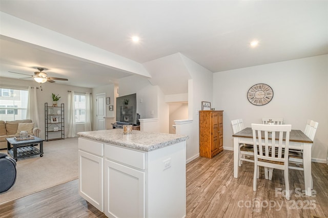 kitchen featuring white cabinets, ceiling fan, a kitchen island, and light hardwood / wood-style flooring