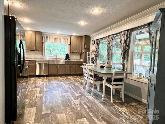 kitchen with a wealth of natural light, sink, tasteful backsplash, black refrigerator with ice dispenser, and stainless steel dishwasher