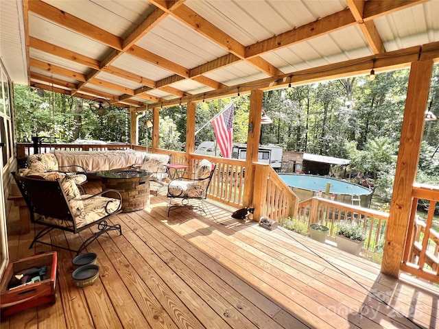 wooden deck featuring a pool and an outdoor living space with a fire pit