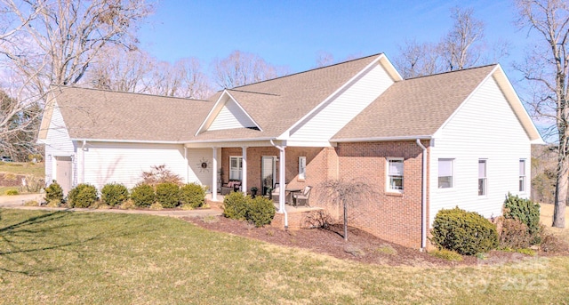 view of front of home featuring a shingled roof, brick siding, and a front lawn