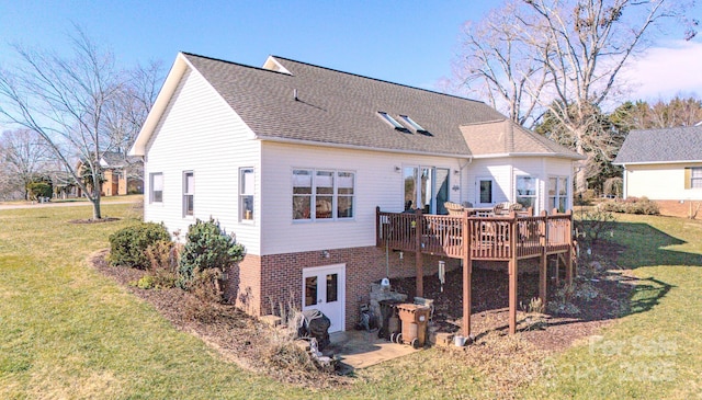 rear view of house with brick siding, a lawn, a shingled roof, and a wooden deck