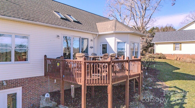 rear view of house with a shingled roof, a lawn, and a wooden deck