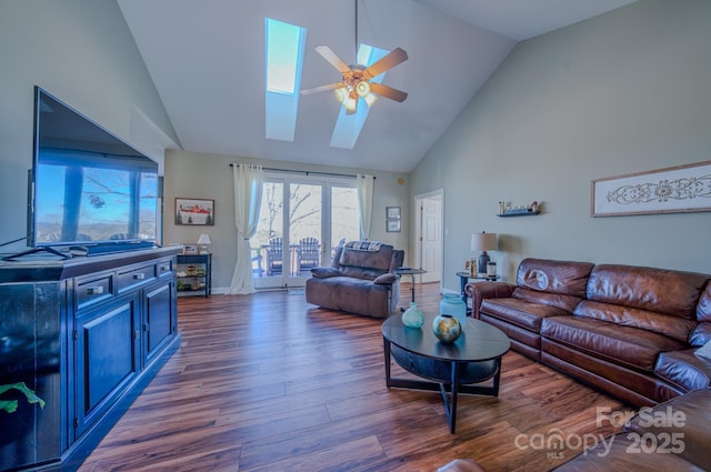 living room featuring ceiling fan, high vaulted ceiling, a skylight, wood finished floors, and baseboards