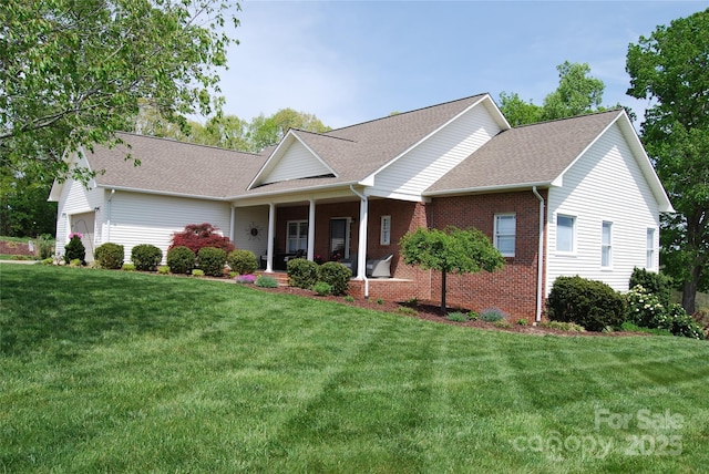 view of front of home with brick siding, an attached garage, a front lawn, and covered porch