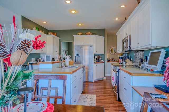 kitchen with white cabinetry, stainless steel appliances, light wood finished floors, and a sink