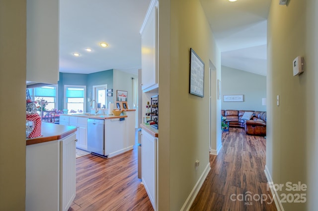 hallway with recessed lighting, wood finished floors, baseboards, and a sink