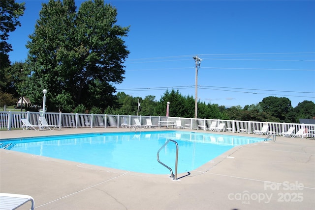 community pool with a patio area and fence