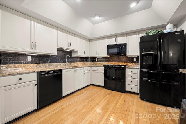 kitchen with black appliances, decorative backsplash, sink, white cabinetry, and light stone countertops