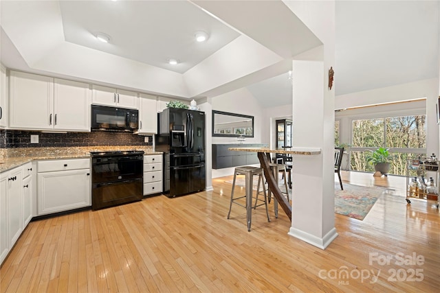 kitchen featuring black appliances, decorative backsplash, light stone countertops, and white cabinetry