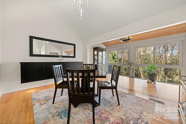 dining area with light hardwood / wood-style flooring and high vaulted ceiling