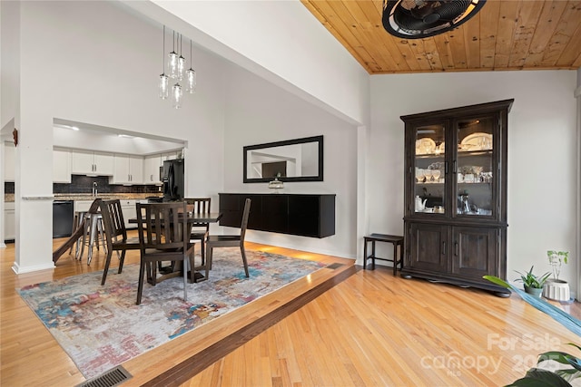 dining room featuring a notable chandelier, light hardwood / wood-style flooring, wood ceiling, and vaulted ceiling