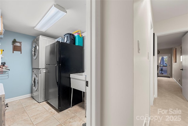 laundry area with stacked washer and clothes dryer and light tile patterned flooring