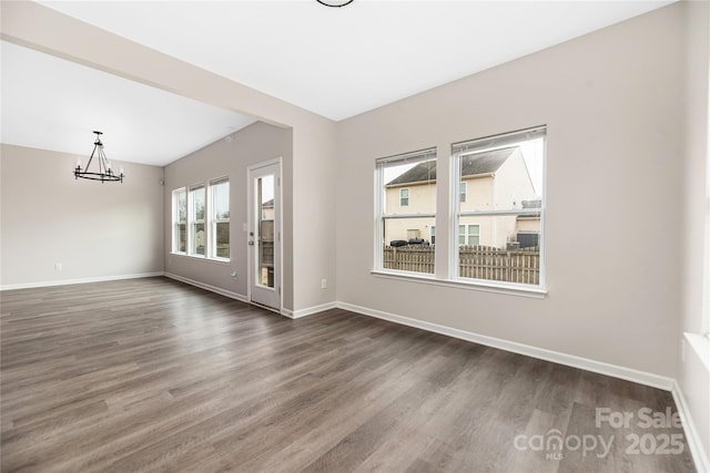 spare room featuring dark wood-type flooring and an inviting chandelier