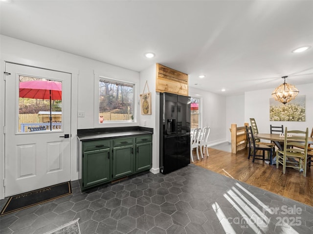 kitchen featuring a notable chandelier, pendant lighting, black refrigerator with ice dispenser, green cabinetry, and dark hardwood / wood-style flooring