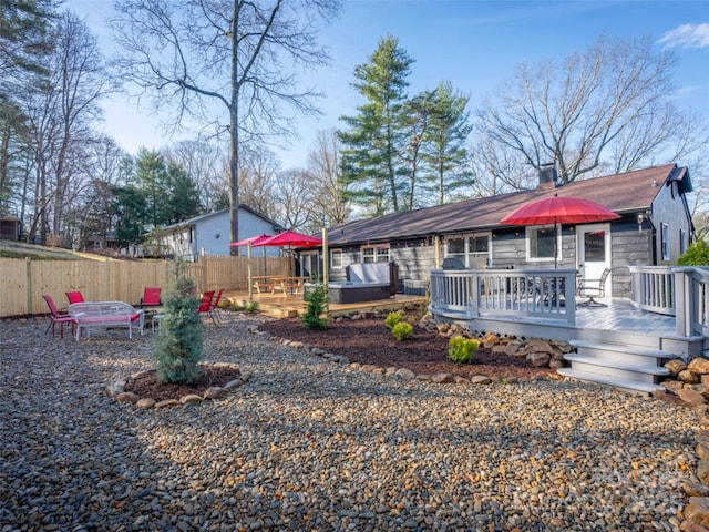 back of house featuring a wooden deck, an outdoor fire pit, and a jacuzzi