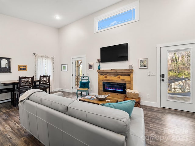 living room featuring a healthy amount of sunlight, a towering ceiling, and dark hardwood / wood-style floors