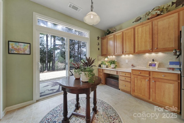 kitchen with backsplash, light tile patterned flooring, built in desk, and hanging light fixtures