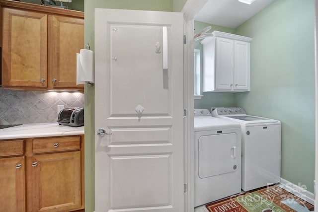 laundry room featuring washer and clothes dryer and cabinets