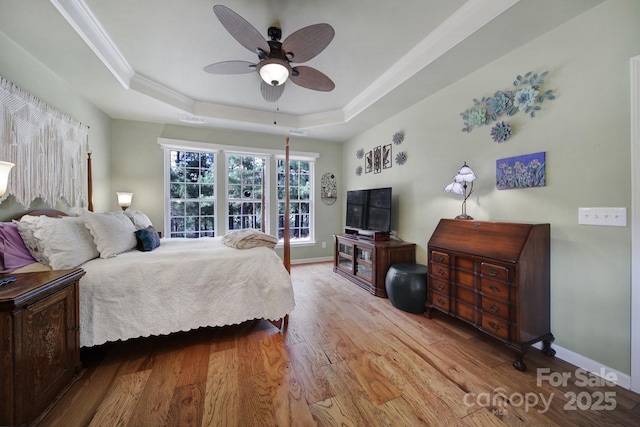 bedroom featuring a tray ceiling, ceiling fan, and light wood-type flooring