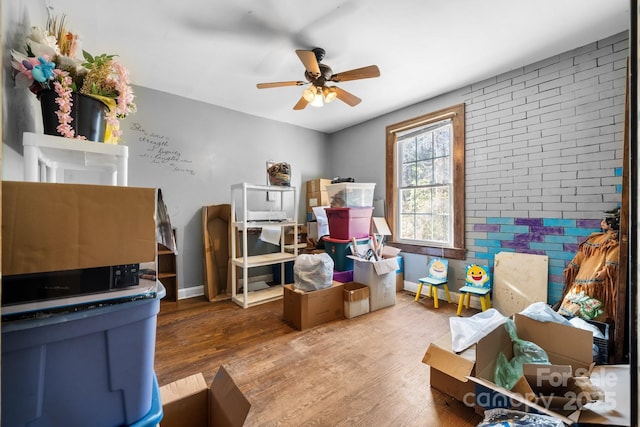 interior space with hardwood / wood-style flooring, ceiling fan, and brick wall