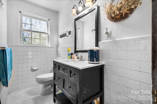 bathroom featuring tile patterned flooring, vanity, toilet, and tile walls