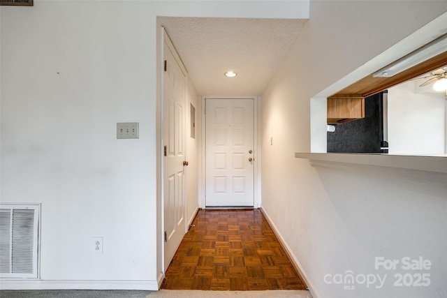 hall featuring dark parquet floors and a textured ceiling