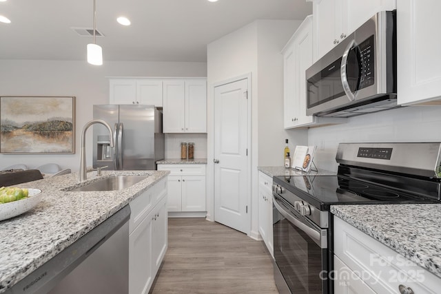 kitchen featuring decorative light fixtures, stainless steel appliances, white cabinetry, and sink