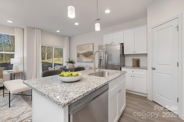 kitchen featuring stainless steel appliances, decorative light fixtures, white cabinetry, decorative backsplash, and a kitchen island with sink