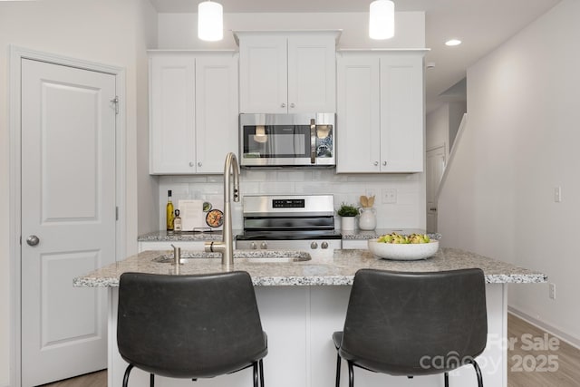 kitchen featuring stainless steel appliances, tasteful backsplash, and an island with sink