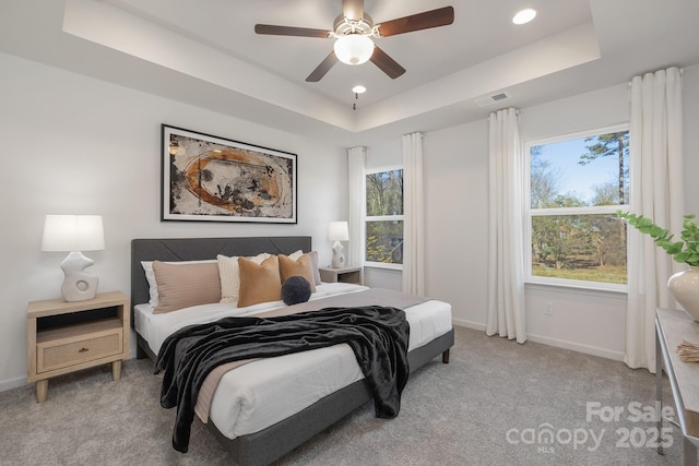 carpeted bedroom with ceiling fan and a tray ceiling