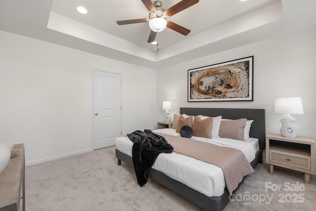 bedroom featuring ceiling fan, light colored carpet, and a raised ceiling