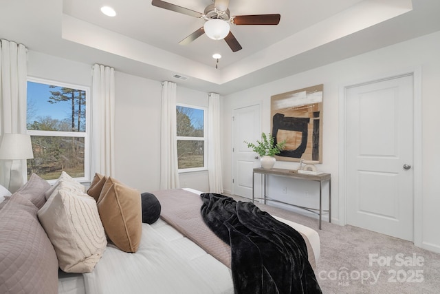 bedroom with ceiling fan, multiple windows, and a raised ceiling