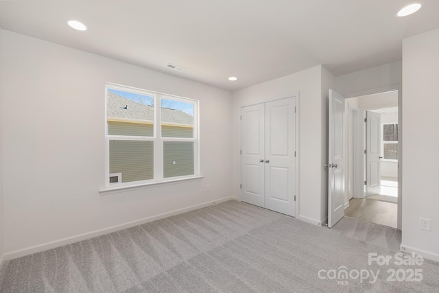 unfurnished bedroom with a closet and light colored carpet