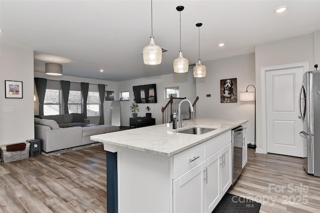 kitchen featuring sink, an island with sink, light stone counters, white cabinetry, and stainless steel appliances