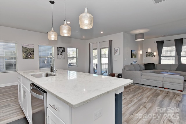 kitchen featuring hanging light fixtures, a kitchen island with sink, sink, and stainless steel dishwasher