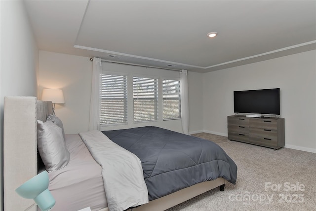 bedroom with a tray ceiling and light colored carpet