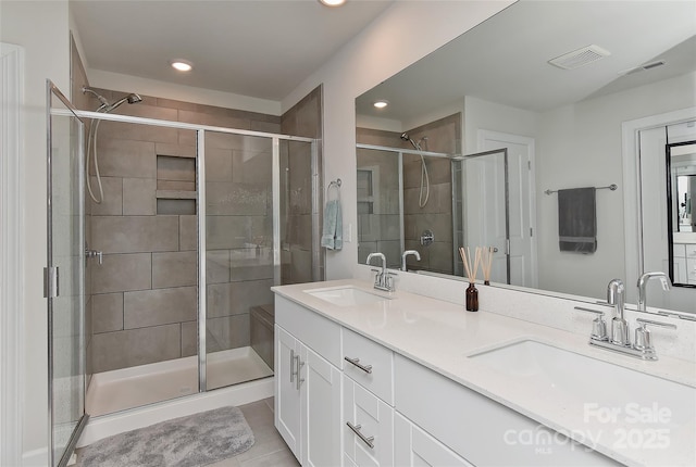 bathroom featuring tile patterned flooring, vanity, and a shower with shower door