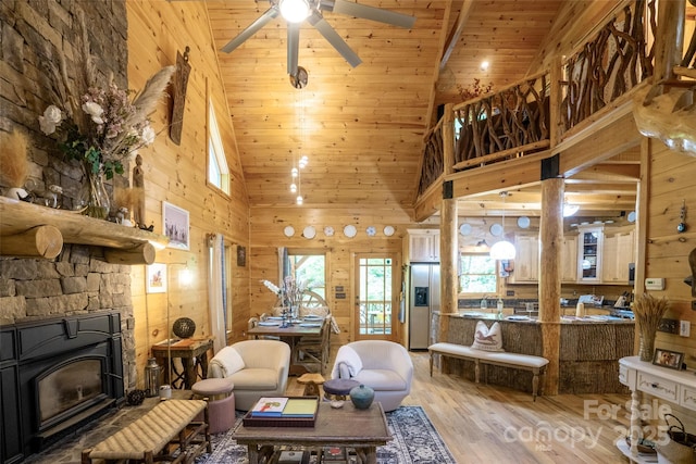 living room with ceiling fan, wooden walls, wood-type flooring, high vaulted ceiling, and wooden ceiling