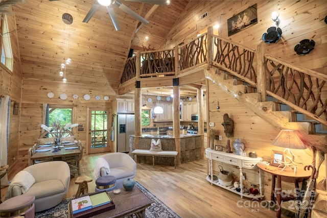 living room featuring light hardwood / wood-style flooring, high vaulted ceiling, wood walls, and wood ceiling