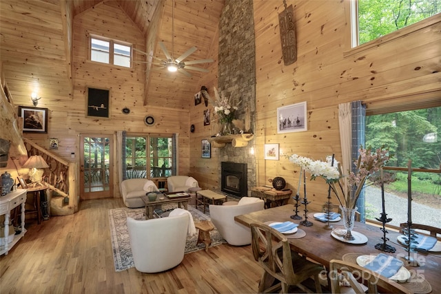 living room with a wood stove, ceiling fan, a healthy amount of sunlight, high vaulted ceiling, and light hardwood / wood-style floors