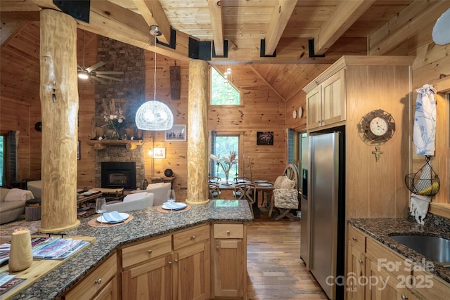 kitchen featuring a wood stove, wood walls, wooden ceiling, and stainless steel refrigerator with ice dispenser