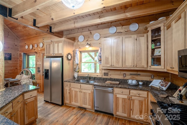 kitchen featuring wood walls, light wood-type flooring, sink, and appliances with stainless steel finishes