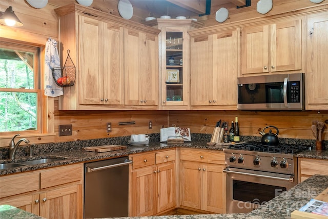 kitchen featuring wooden walls, sink, light brown cabinets, and appliances with stainless steel finishes