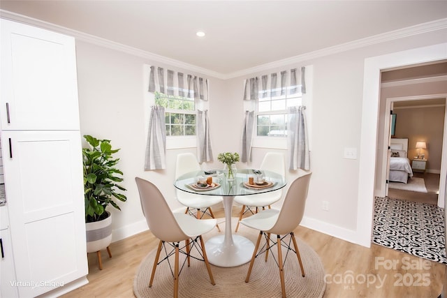 dining room with crown molding and light hardwood / wood-style flooring