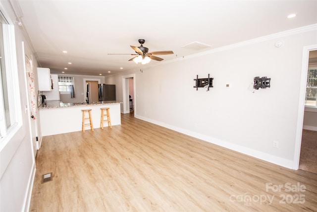 unfurnished living room featuring ornamental molding, ceiling fan, and light hardwood / wood-style floors