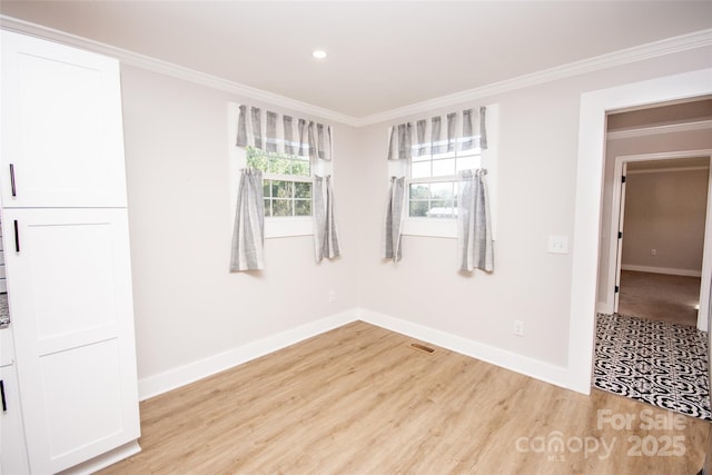 empty room featuring crown molding and light wood-type flooring