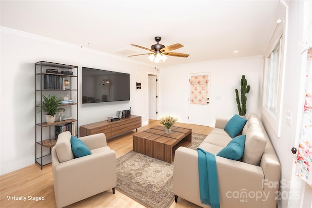 living room featuring ornamental molding, ceiling fan, and light wood-type flooring