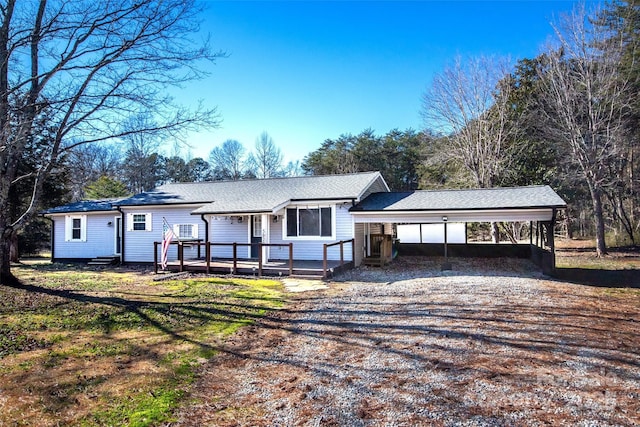 view of front facade with driveway, a carport, and a wooden deck