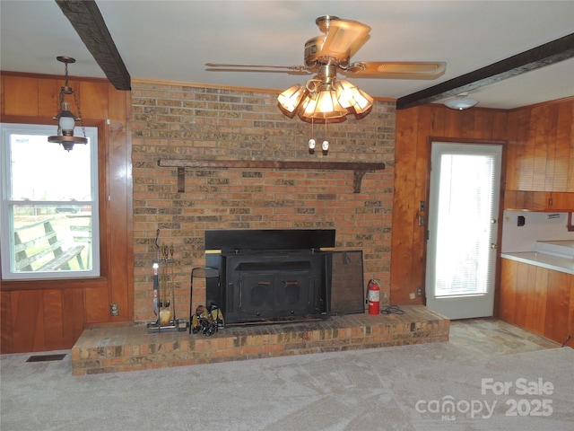 unfurnished living room featuring carpet, beam ceiling, and wood walls