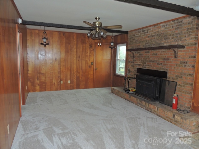 unfurnished living room featuring ceiling fan, light colored carpet, and wooden walls